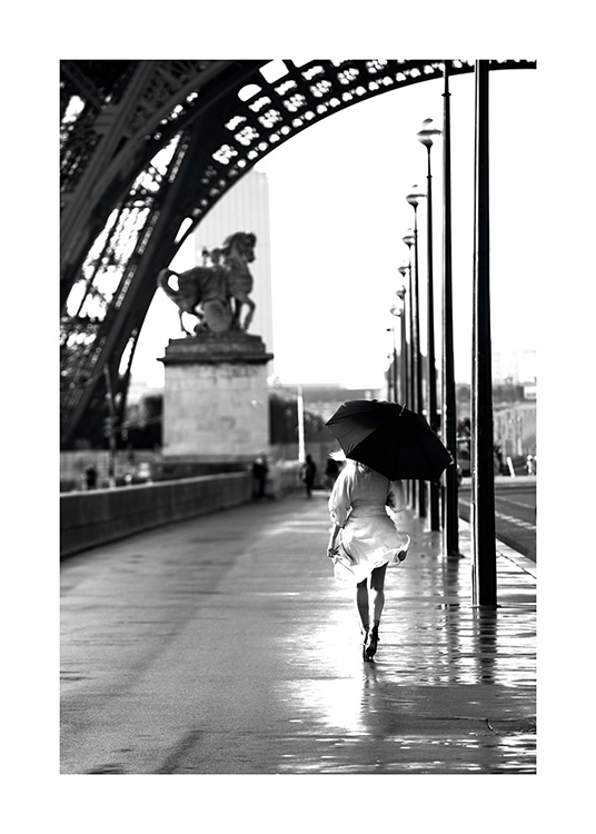  – Czarno-białe zdjęcie kobiety spacerującej z parasolem pod Wieżą Eiffla