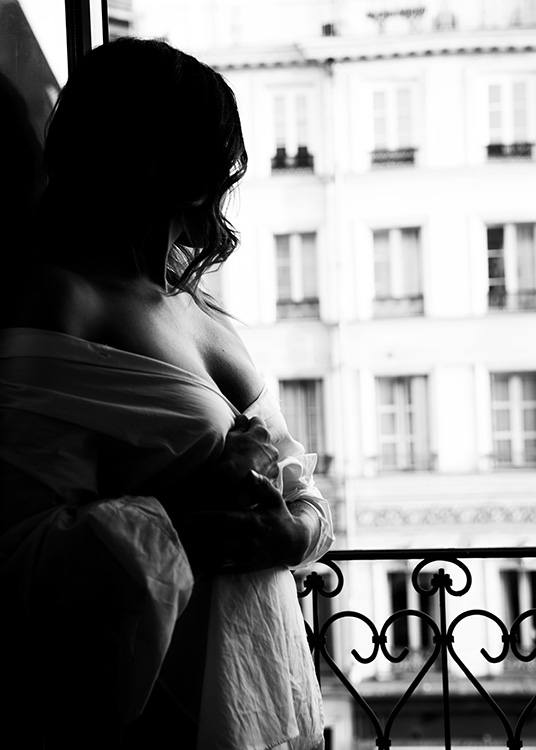– Czarno–biała fotografia przedstawiająca kobietę stojącą przy oknie